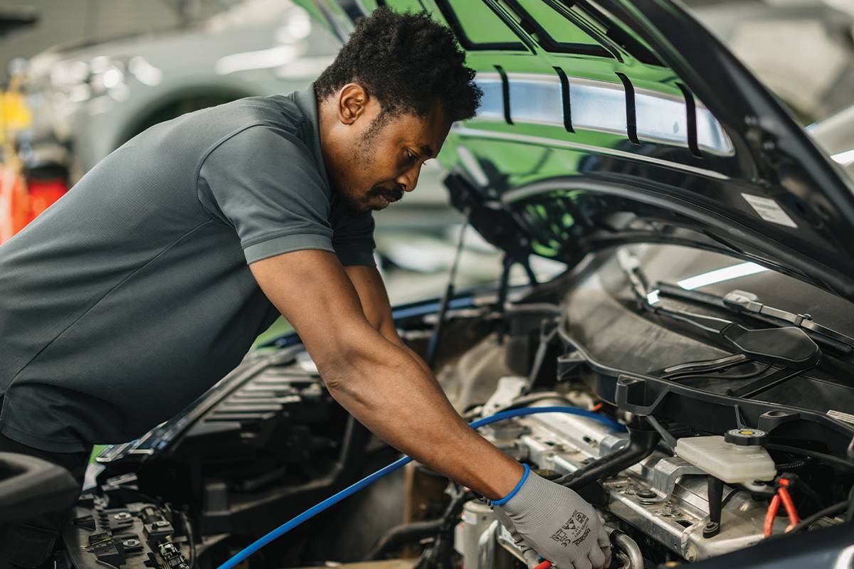 EVS Oman technician performing electric vehicle battery maintenance in Seeb workshop